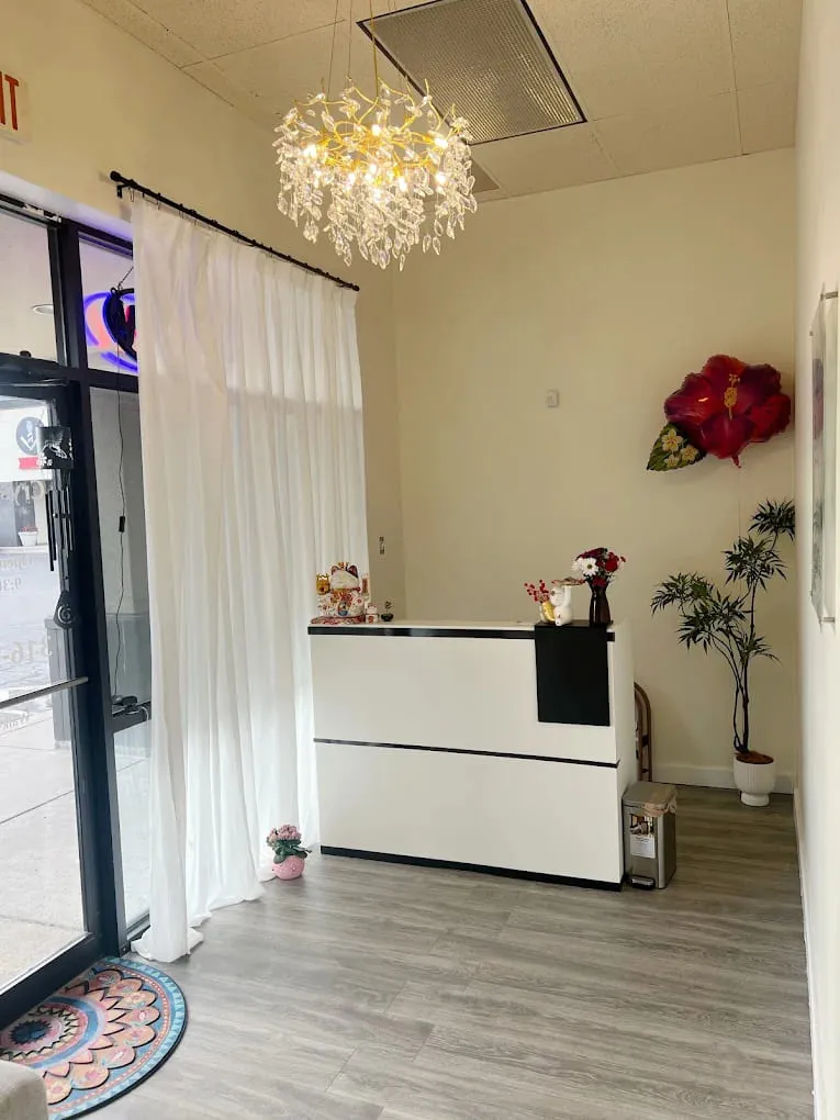 The reception counter in white, lit by a leaf-cut chandelier, with the glass entrance and its sheer curtain alongside